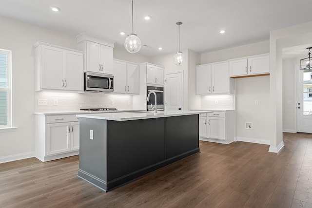 kitchen with stainless steel appliances, a center island with sink, and white cabinets