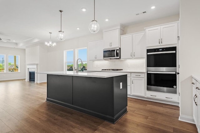 kitchen with stainless steel appliances, an island with sink, sink, and white cabinets