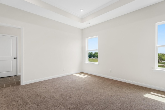 unfurnished room with crown molding, a tray ceiling, dark carpet, and a wealth of natural light