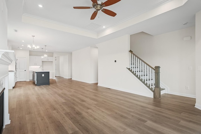 unfurnished living room with hardwood / wood-style flooring, ornamental molding, sink, and a tray ceiling