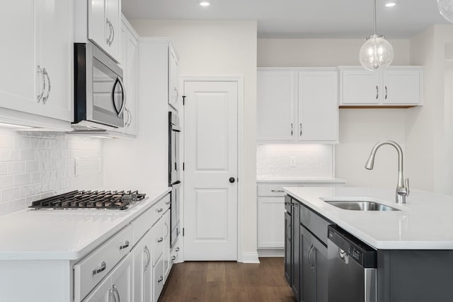 kitchen featuring white cabinetry, stainless steel appliances, sink, and hanging light fixtures