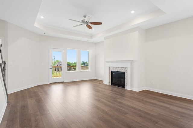 unfurnished living room featuring ceiling fan, dark hardwood / wood-style flooring, and a tray ceiling