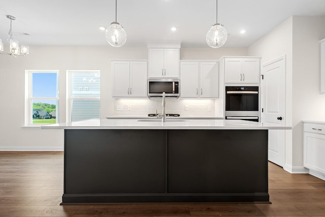 kitchen featuring white cabinetry, decorative light fixtures, and a center island with sink