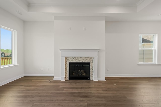 unfurnished living room featuring a high end fireplace, dark hardwood / wood-style flooring, and a raised ceiling