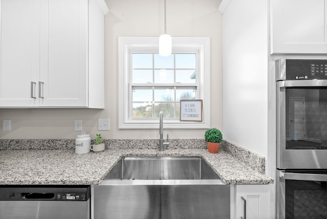 kitchen featuring light stone countertops, white cabinetry, appliances with stainless steel finishes, and hanging light fixtures