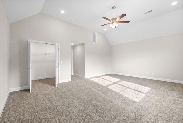 unfurnished bedroom with vaulted ceiling, a walk in closet, carpet floors, and ceiling fan