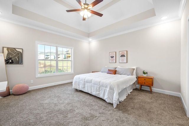 bedroom featuring crown molding, a tray ceiling, carpet floors, and ceiling fan