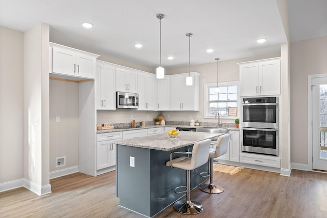 kitchen featuring a kitchen island, appliances with stainless steel finishes, sink, and white cabinets