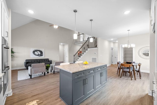 kitchen with gray cabinets, white cabinetry, a kitchen island, decorative light fixtures, and light wood-type flooring