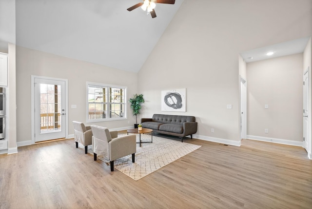 living room with ceiling fan, high vaulted ceiling, and light wood-type flooring