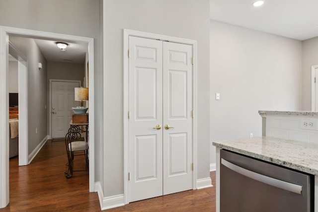 kitchen featuring light stone counters, dark wood-type flooring, and stainless steel dishwasher