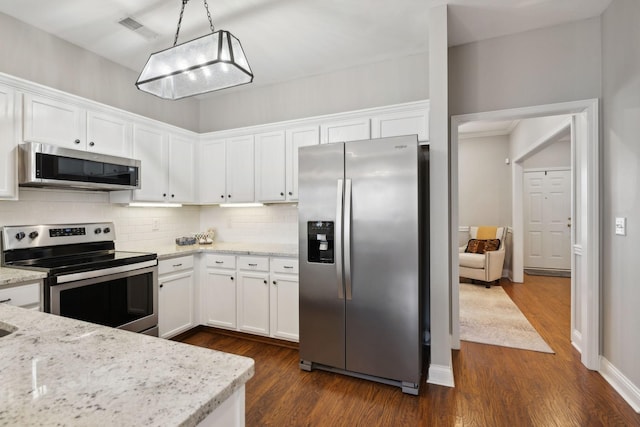 kitchen featuring decorative light fixtures, white cabinets, decorative backsplash, stainless steel appliances, and light stone countertops