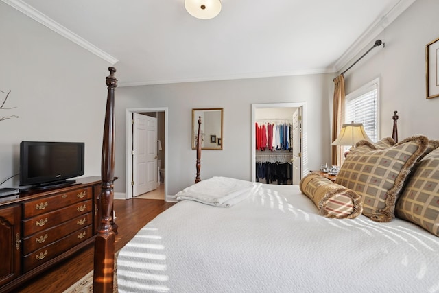 bedroom with crown molding, a walk in closet, dark hardwood / wood-style floors, and a closet