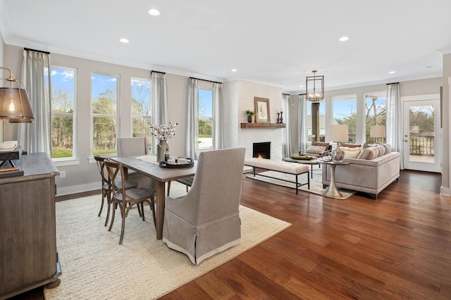 dining space with crown molding, a brick fireplace, and wood-type flooring