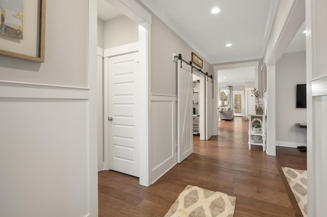 corridor with dark hardwood / wood-style flooring, crown molding, and a barn door