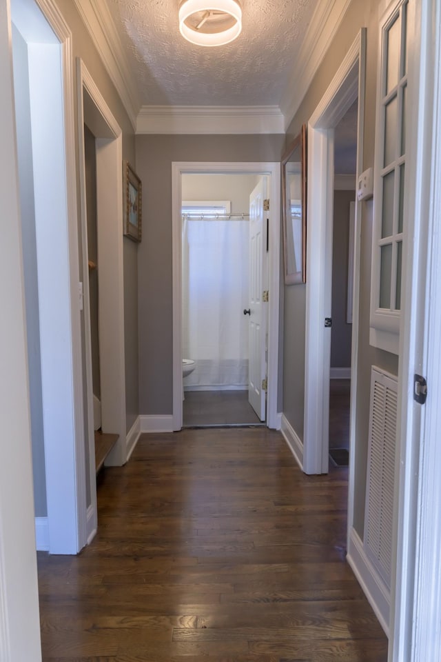 corridor with ornamental molding, dark wood-type flooring, and a textured ceiling