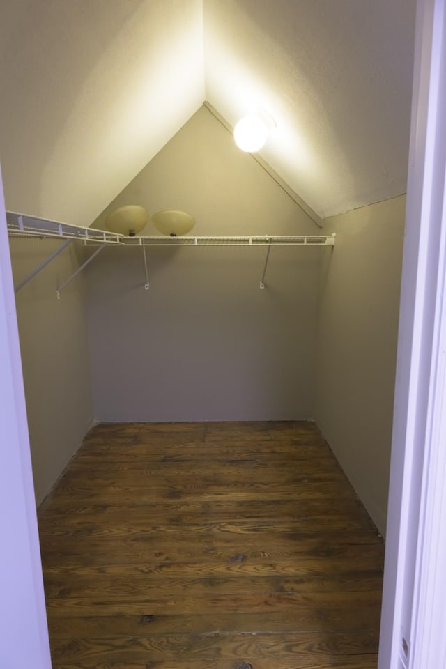 walk in closet with dark wood-type flooring and vaulted ceiling