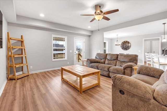 living room with sink, ceiling fan, and light wood-type flooring