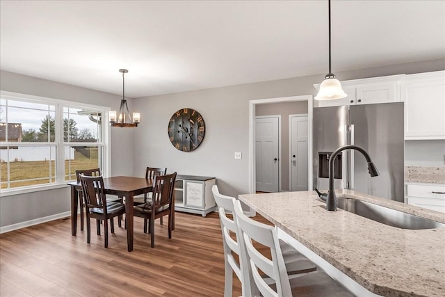 kitchen with pendant lighting, light stone countertops, sink, and white cabinets