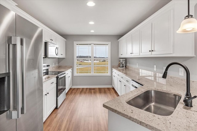 kitchen featuring appliances with stainless steel finishes, sink, hanging light fixtures, and white cabinets