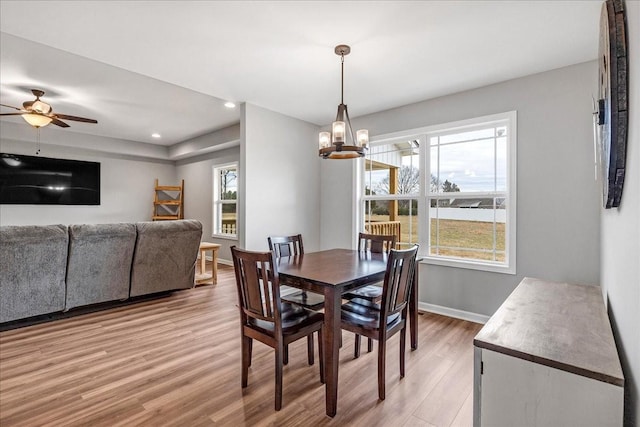 dining space with hardwood / wood-style floors and ceiling fan with notable chandelier