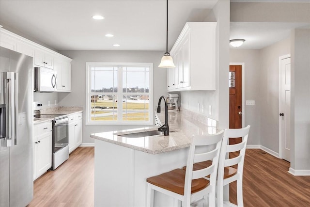 kitchen with white cabinetry, appliances with stainless steel finishes, light stone counters, and hanging light fixtures