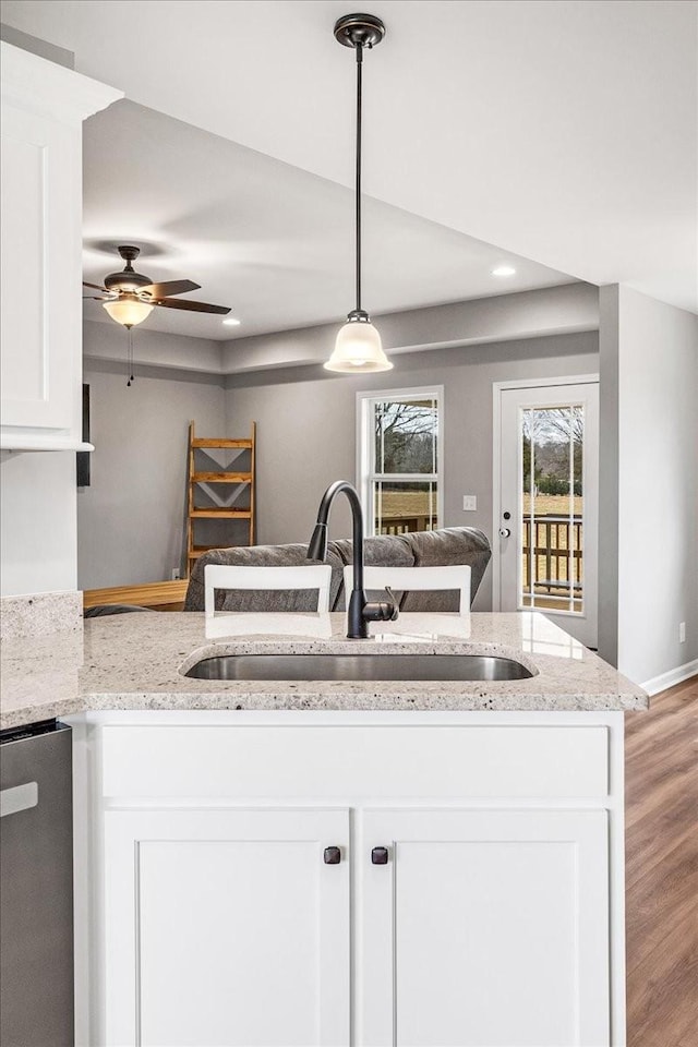 kitchen with sink, pendant lighting, white cabinets, and light stone counters