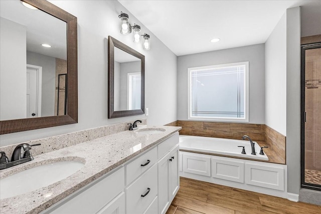 bathroom with hardwood / wood-style flooring, shower with separate bathtub, and vanity