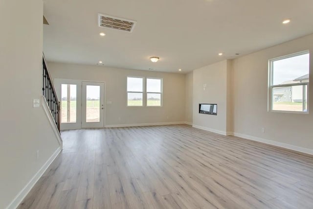 unfurnished living room featuring a healthy amount of sunlight and light hardwood / wood-style flooring