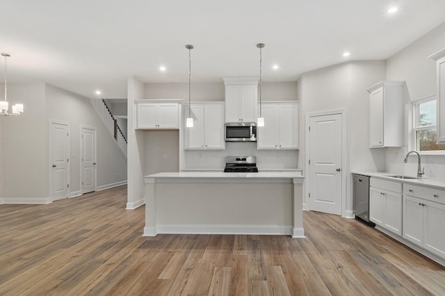 kitchen with pendant lighting, white cabinetry, sink, a center island, and stainless steel appliances