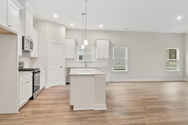 kitchen with white cabinetry, sink, hanging light fixtures, a center island, and stainless steel appliances