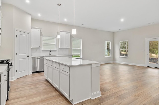 kitchen with a center island, stainless steel dishwasher, black gas stove, pendant lighting, and white cabinets