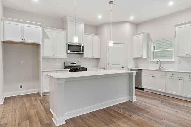 kitchen with stainless steel appliances, a center island, sink, and white cabinets