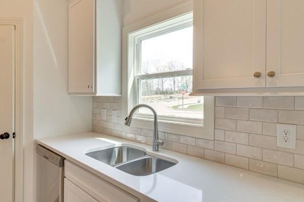 kitchen with white cabinetry, stainless steel dishwasher, sink, and decorative backsplash