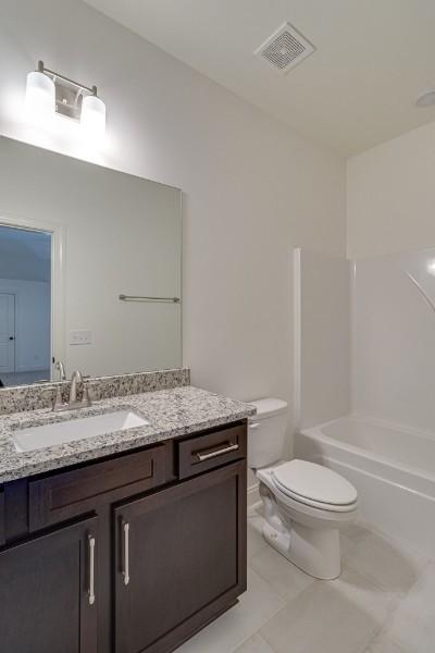 full bathroom with vanity, toilet,  shower combination, and tile patterned flooring