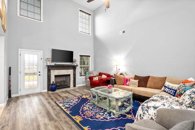 living room featuring hardwood / wood-style floors, a high end fireplace, a wealth of natural light, and ceiling fan