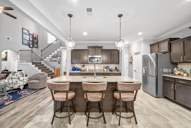 kitchen with dark brown cabinetry, stainless steel appliances, light stone countertops, and sink