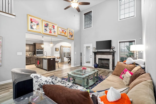 living room featuring ceiling fan, light hardwood / wood-style flooring, and a high ceiling