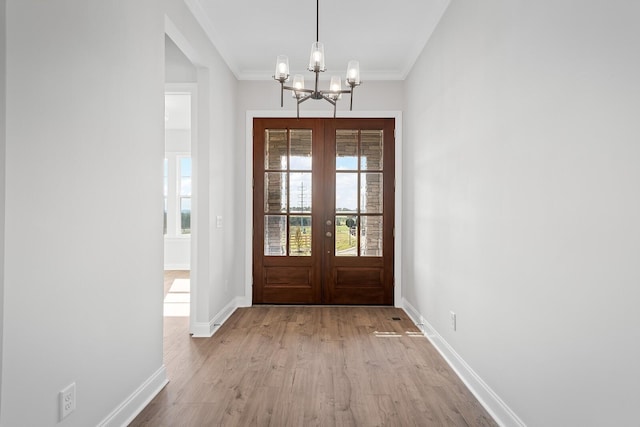 doorway with baseboards, crown molding, french doors, light wood-style floors, and a chandelier