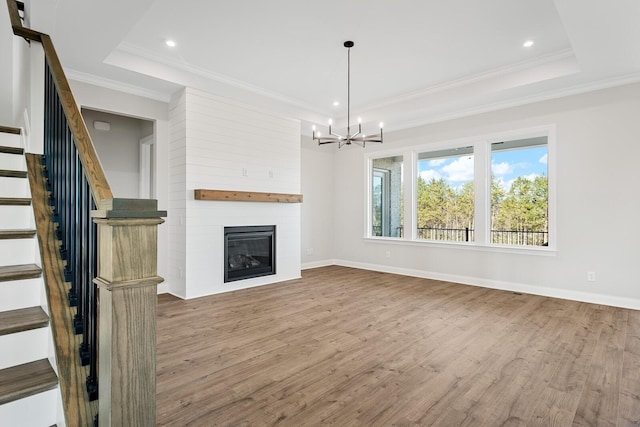 unfurnished living room with ornamental molding, hardwood / wood-style floors, and a tray ceiling