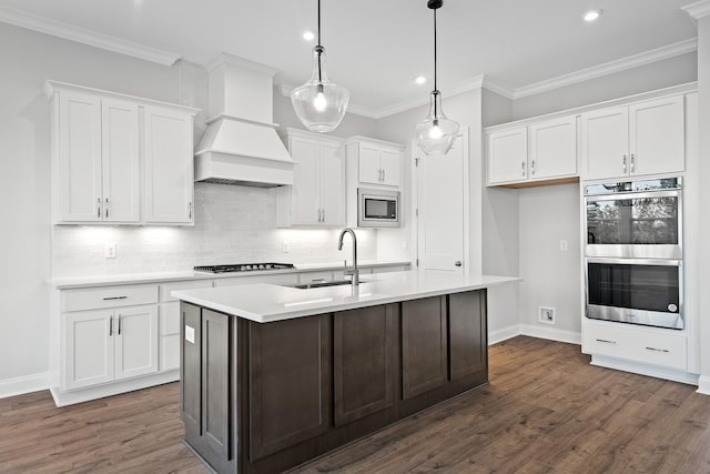 kitchen featuring custom exhaust hood, white cabinetry, appliances with stainless steel finishes, and decorative light fixtures