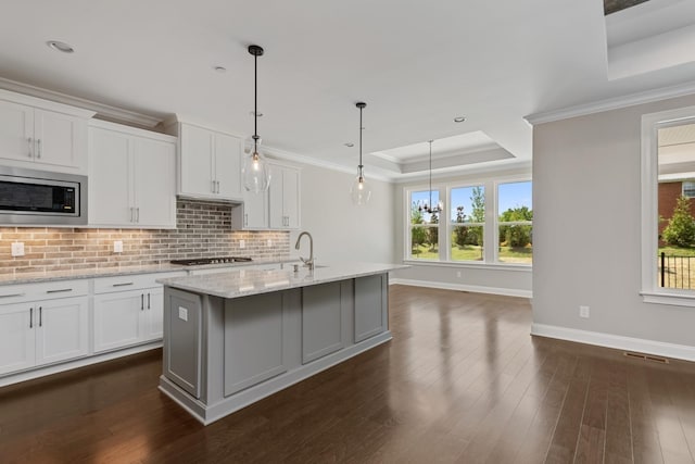 kitchen with stainless steel microwave, a tray ceiling, and white cabinets