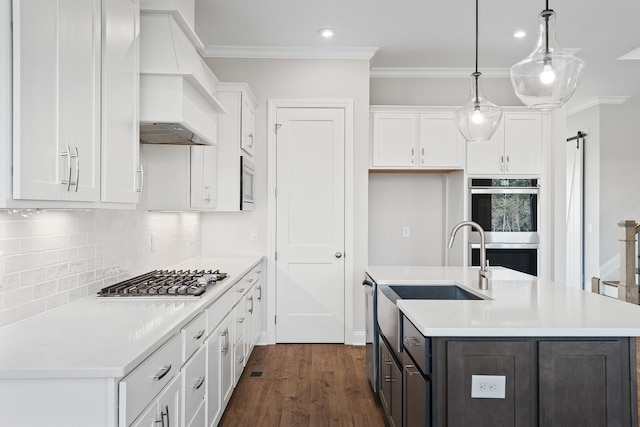 kitchen featuring white cabinetry, appliances with stainless steel finishes, custom range hood, and pendant lighting