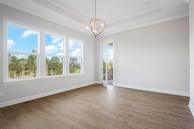 empty room with wood-type flooring, crown molding, a chandelier, and a tray ceiling