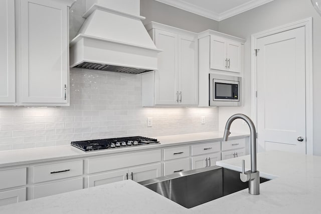 kitchen featuring sink, crown molding, white cabinetry, stainless steel appliances, and custom range hood