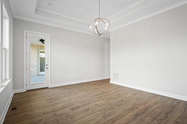 empty room with wood-type flooring, a notable chandelier, crown molding, and a tray ceiling