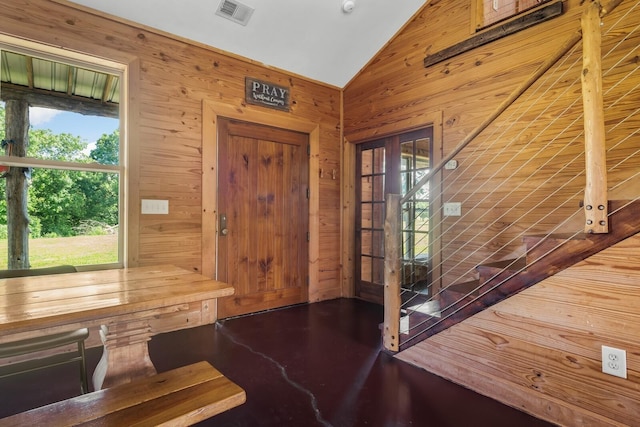 entryway with lofted ceiling, wooden walls, and plenty of natural light