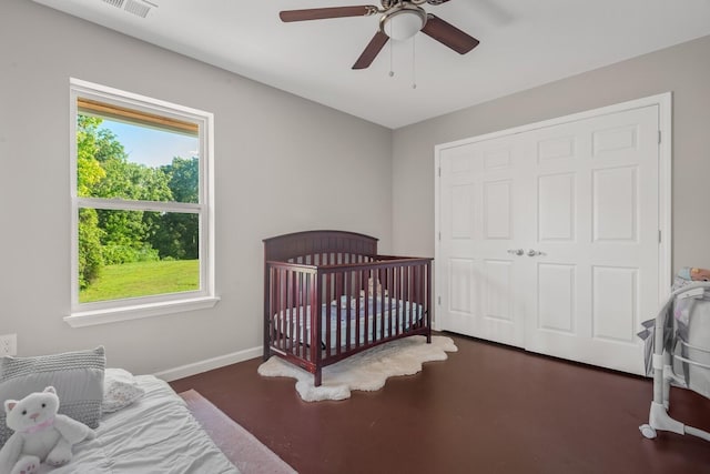 bedroom featuring a nursery area, ceiling fan, and a closet