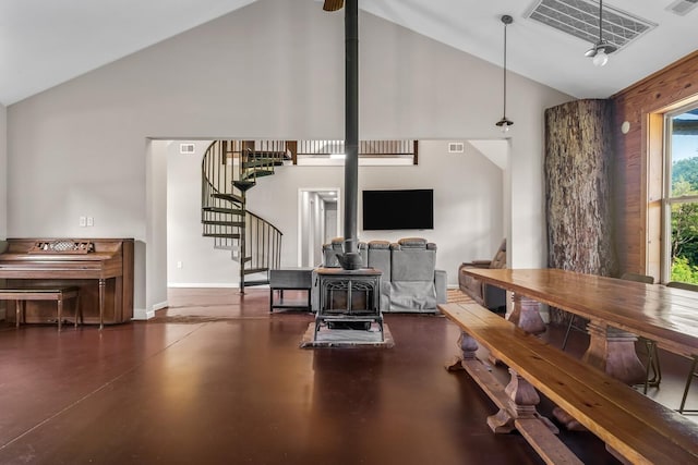 living room featuring a wood stove and high vaulted ceiling