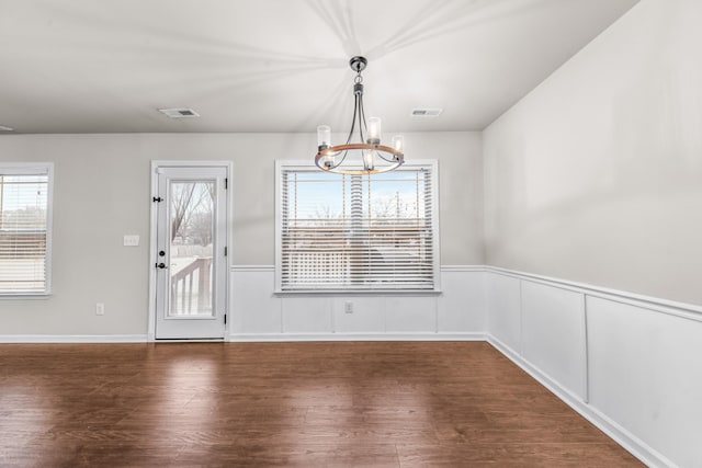 unfurnished dining area featuring an inviting chandelier and dark hardwood / wood-style floors